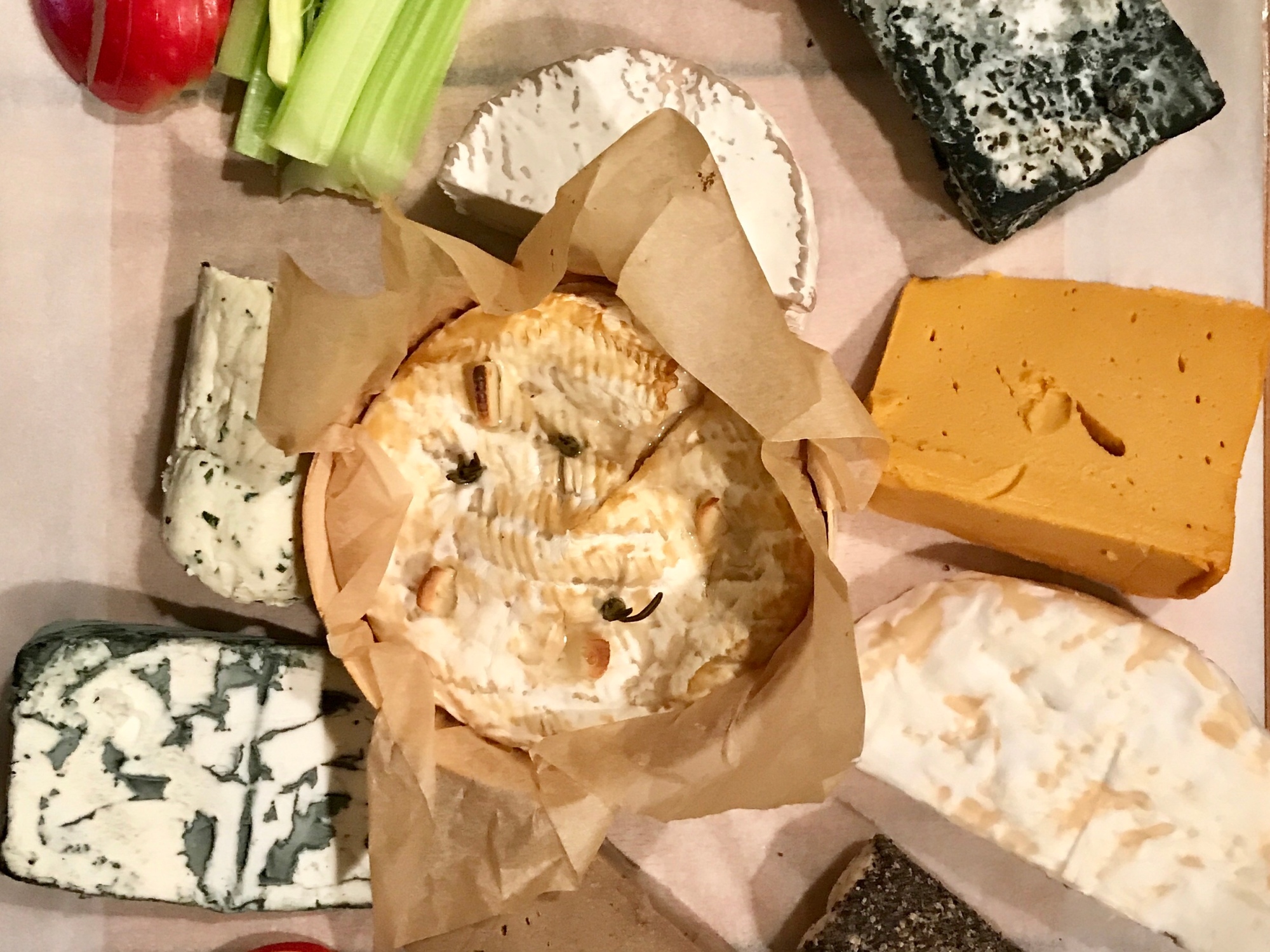9 Vegan cheeses laid on a board with fruit and crackers surrounding them